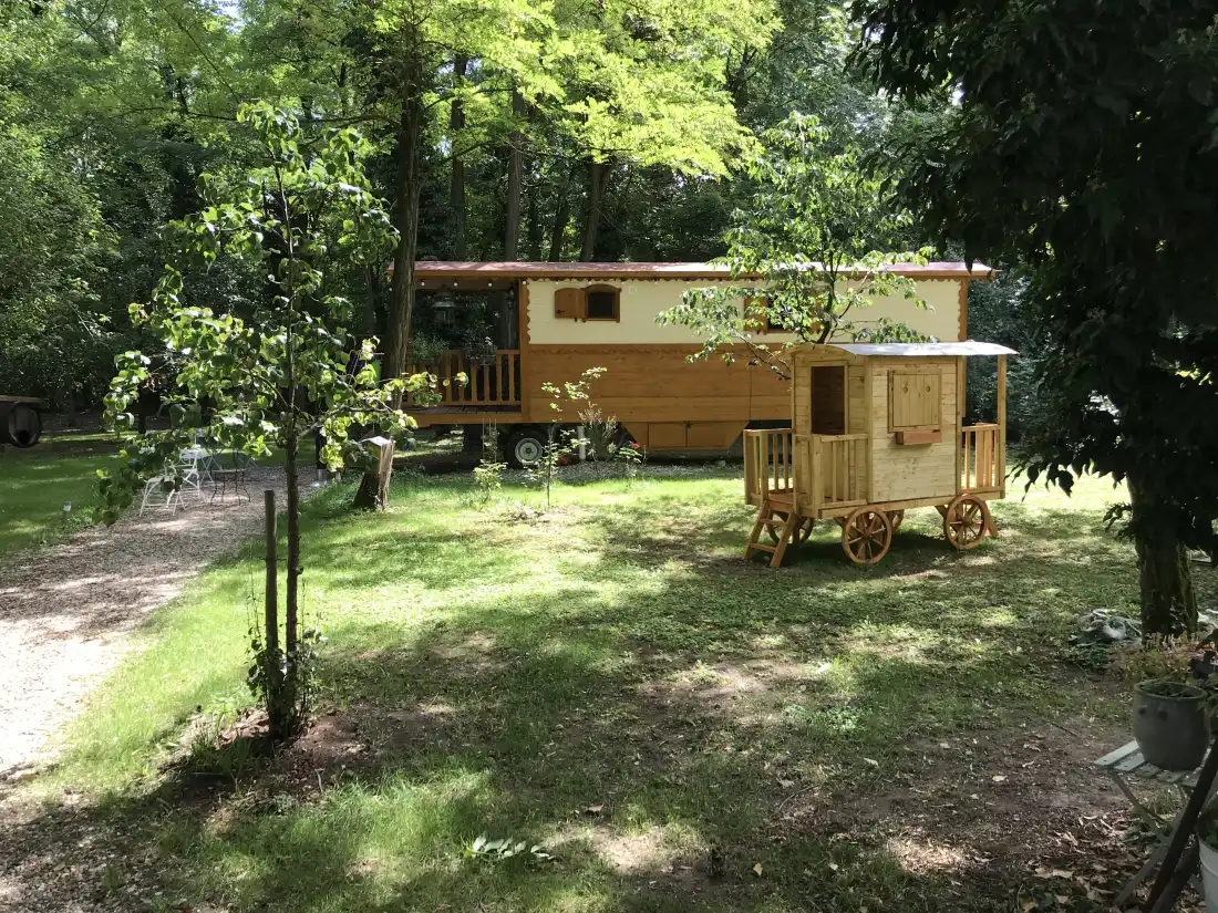 Die hölzerne Roulotte im Sommer unter den Bäumen des Gartens